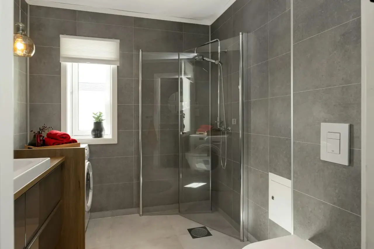 Frisch gefliestes Bad mit bodengleicher Dusche und grauen Großformatfliesen